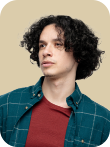 Young man with curly hair wearing a plaid shirt and red t-shirt, looking to the side